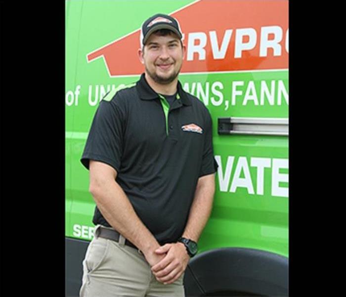 Male Production Manager Caleb Weaver standing in front of SERVPRO truck